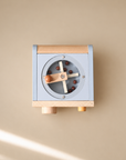 Top-down view of wooden coffee maker toy with rotating coffee beans, cups and accessories on beige background.