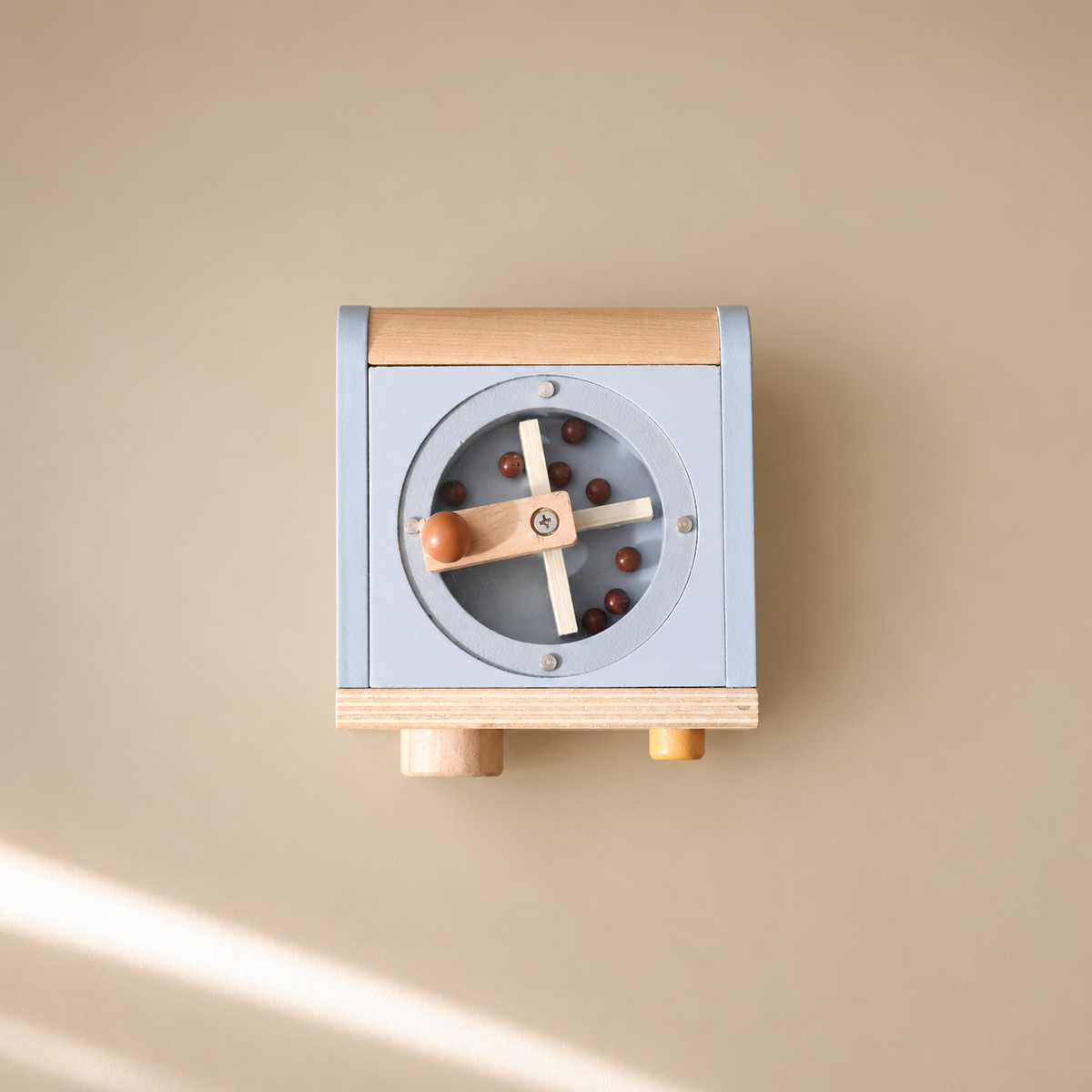 Top-down view of wooden coffee maker toy with rotating coffee beans, cups and accessories on beige background.